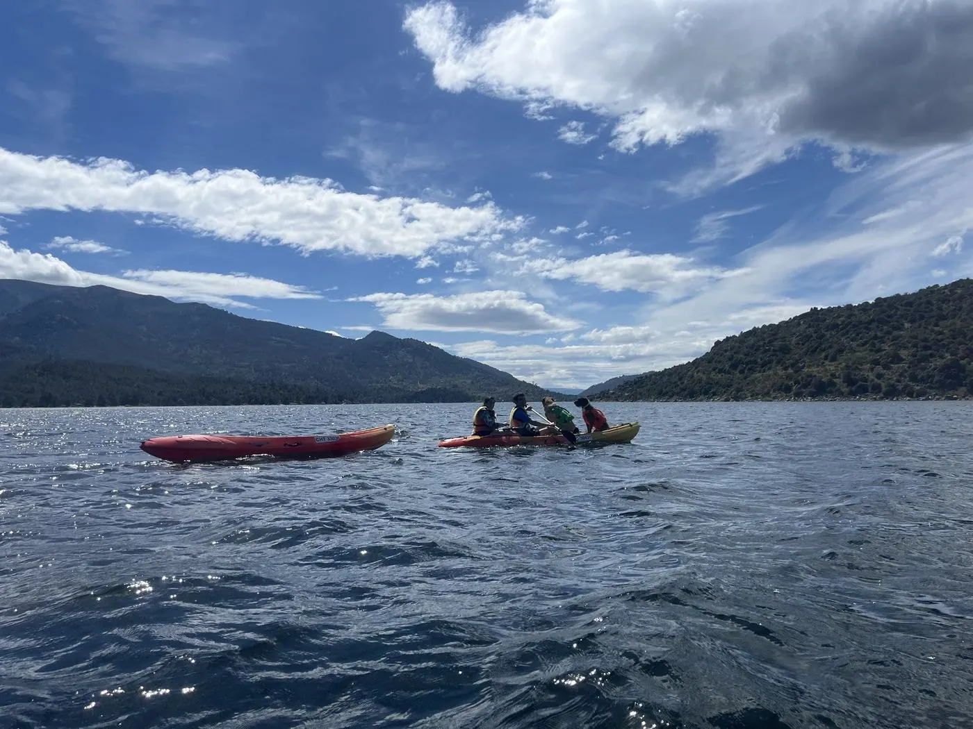 Kayaks a lo lejos en el embalse de El Burguillo bajo un cielo con nubes